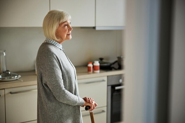 Femme âgée de rêve debout dans la cuisine