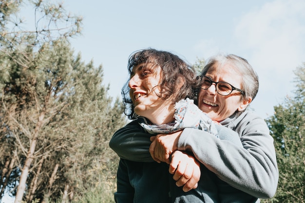 Femme âgée et sa fille souriante et s'amusant dans la forêt pendant la joyeuse fête des mères