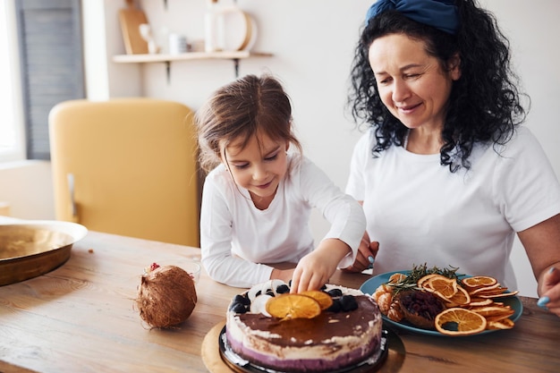 Femme âgée avec sa petite-fille préparant un gâteau diététique dans la cuisine