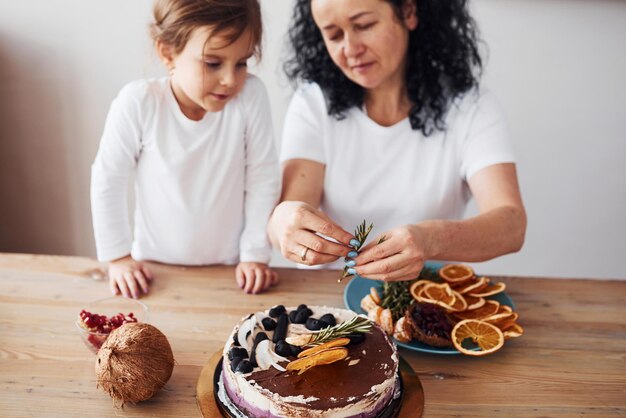 Femme âgée avec sa petite-fille préparant un gâteau diététique dans la cuisine