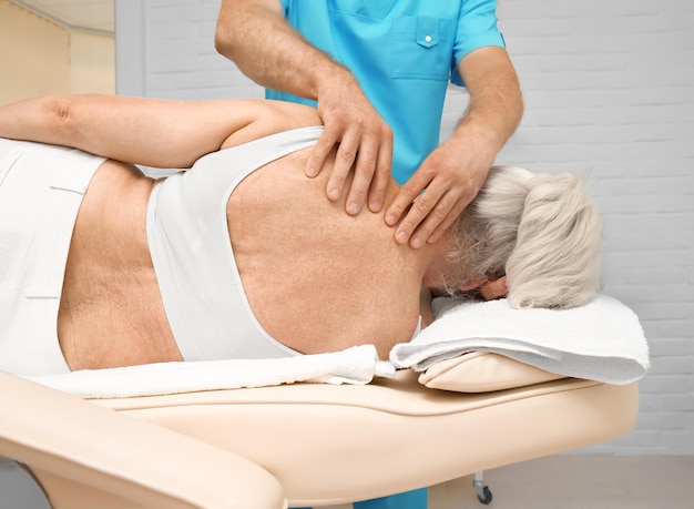 Photo femme âgée se faisant masser au bureau de physiothérapie