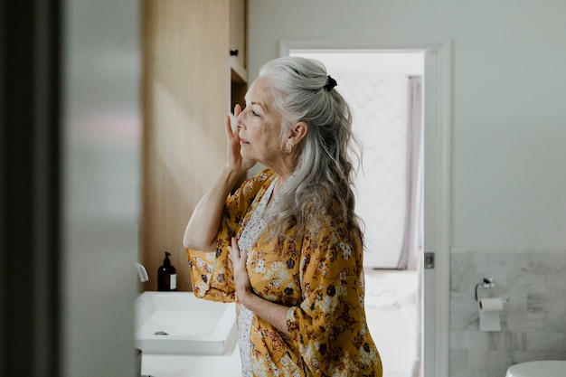 Femme âgée se maquiller devant un miroir