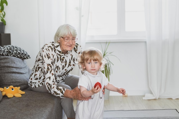 Femme âgée avec son petit-fils jouant à la maison sur le canapé