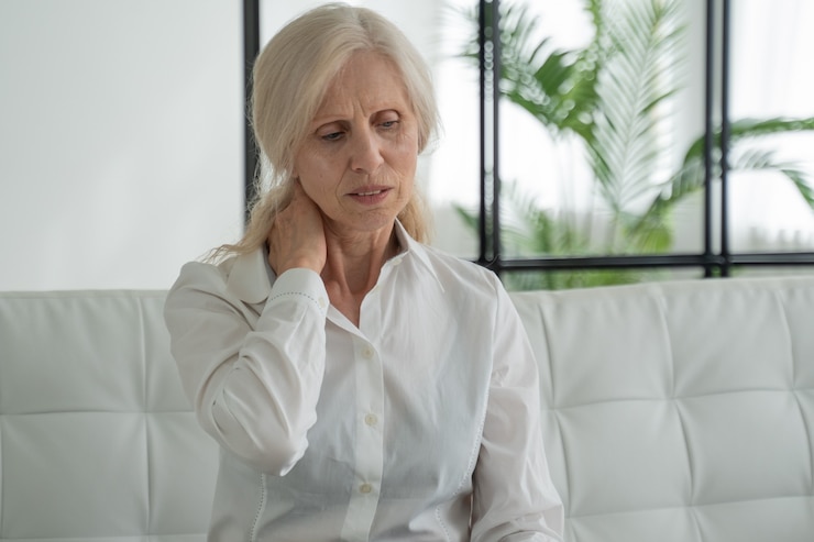 Photo femme âgée souffrant de douleurs au cou assise sur le canapé à la maison