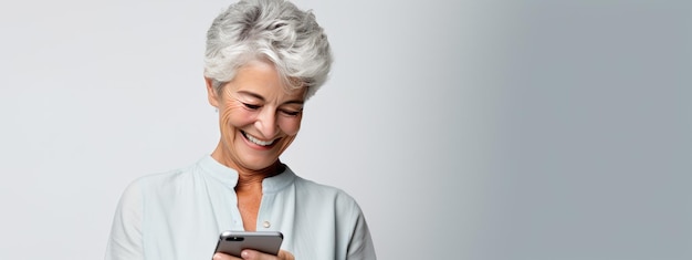 Une femme âgée souriant et riant avec son téléphone sur un fond coloré.