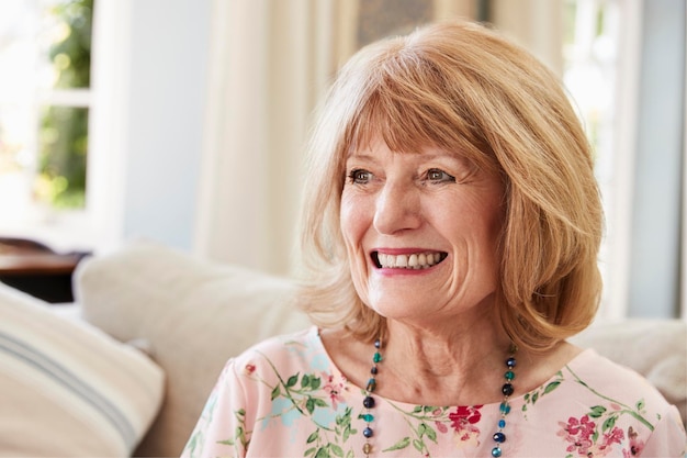 Photo femme âgée souriante assise sur un canapé à la maison