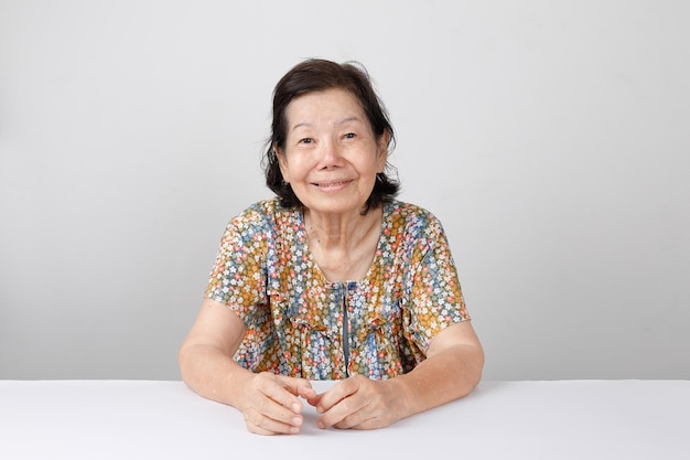 Femme âgée souriante assise sur fond blanc