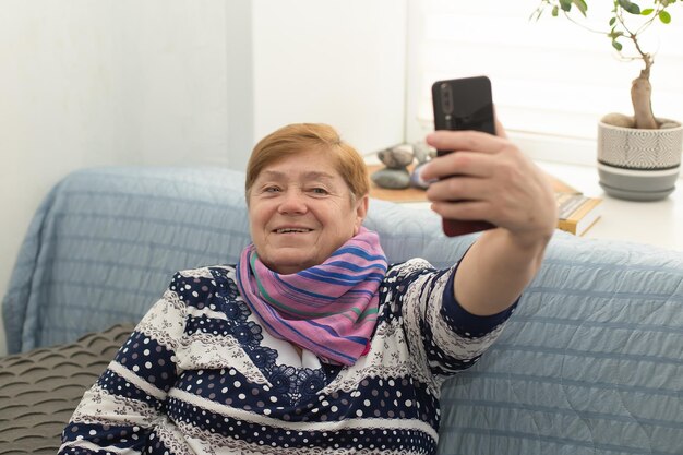 Une femme âgée souriante et heureuse à la maison prend un selfie Émotions positives