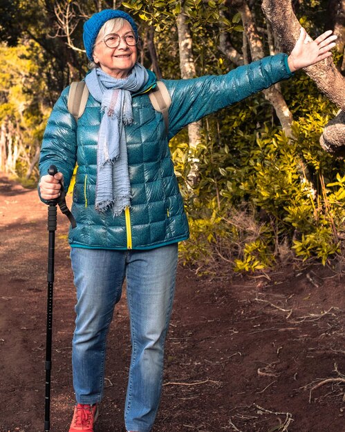 Une femme âgée souriante jouissant de la liberté à l'extérieur se promène dans une forêt de montagne tenant un sac à dos