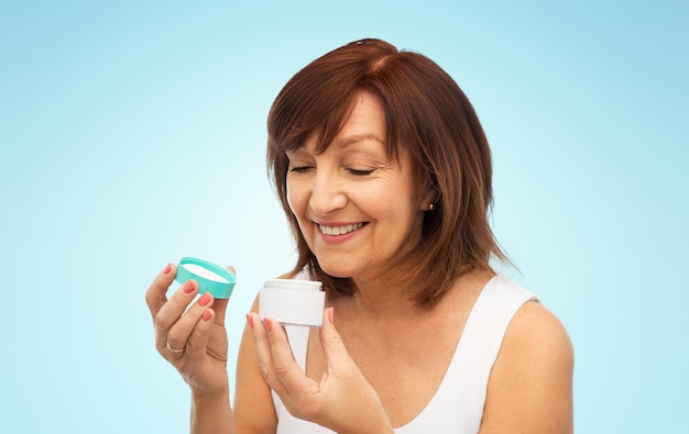 une femme âgée souriante avec un pot de crème