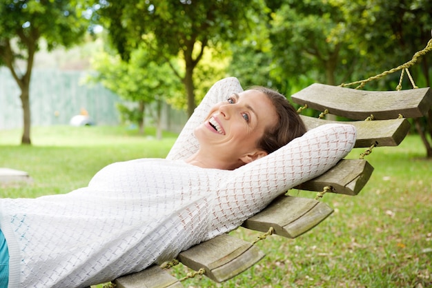 Femme âgée souriante se détendre sur le hamac en plein air