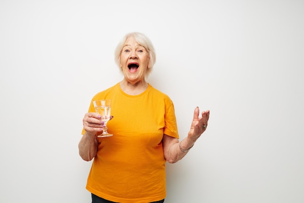 Femme âgée souriante tenant un verre d'eau santé fond clair