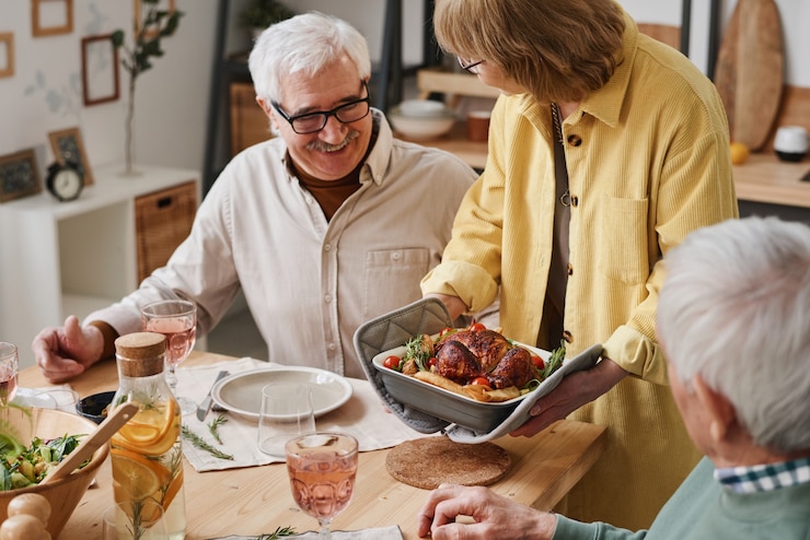 Photo femme âgée tenant un plat et le servant pour un dîner de fête pendant le dîner avec ses amis