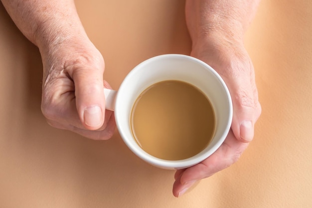 Une femme âgée tient le café du matin avec du lait à la main.