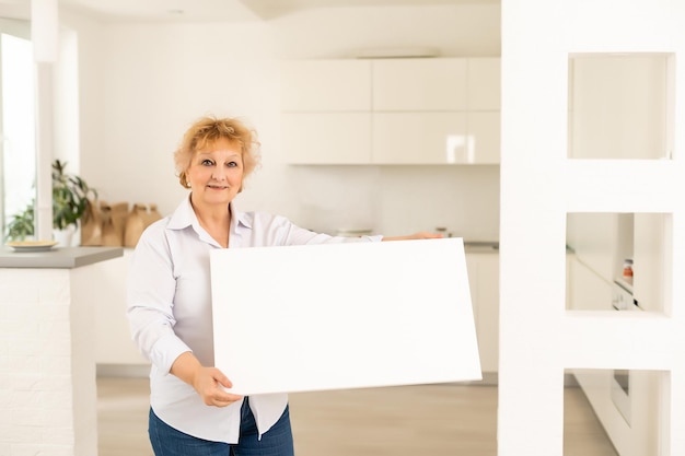 femme âgée et toile vierge. Copiez l'espace sur le tableau de toile pour l'image ou le message. affiche maquette.