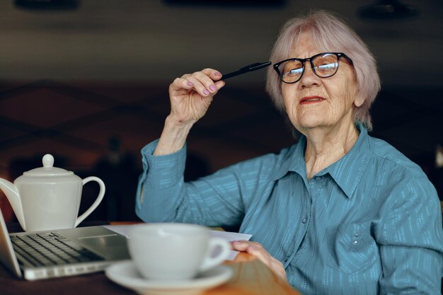 Femme âgée travaillant devant un écran d'ordinateur portable assis