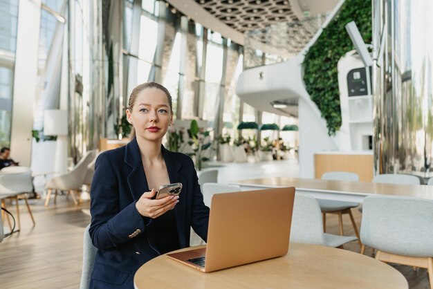 Une femme agent immobilier dans un blazer travaille à la table dans le hall moderne