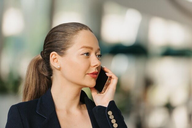 Une femme agent immobilier dans un blazer travaille à la table dans le hall moderne