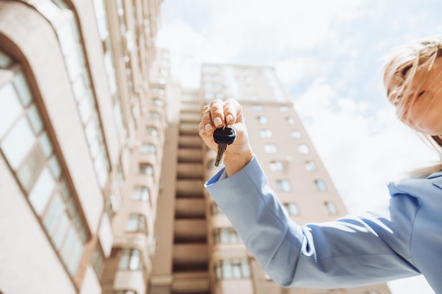 Une femme agent immobilier détient la clé d'un appartement dans une nouvelle maison le propriétaire de la propriété fait une vente achète le concept d'une transaction immobilière en gros plan