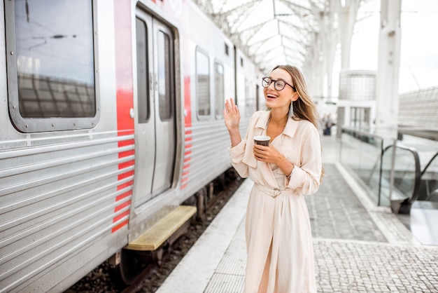 Femme agitant la main en disant au revoir près du train à la gare