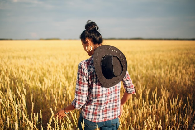 Femme agricultrice américaine portant une chemise à carreaux chapeau de cow-boy et un jean au champ de blé