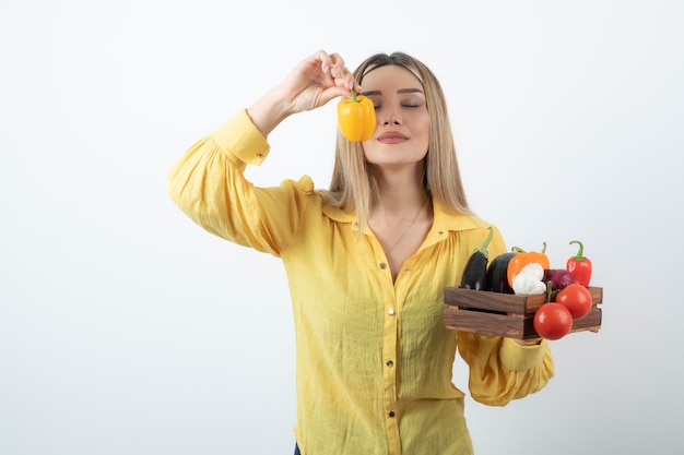 Femme agricultrice debout et tenant une caisse en bois pleine d'une variété de légumes biologiques