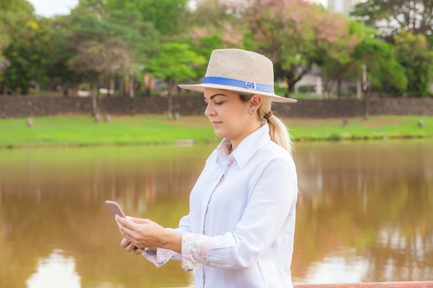 Femme agroalimentaire portant un chapeau et un jean à la fin d'une journée de travail tenant un téléphone portable