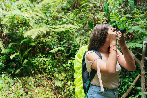 Femme à l'aide d'appareil photo dans la forêt tropicale