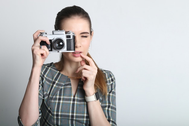 Femme à l'aide d'un appareil photo vintage avec l'appareil photo levé à ses yeux en regardant dans le viseur