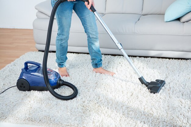 Femme à l&#39;aide d&#39;un aspirateur sur tapis