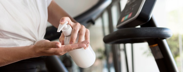 Femme à L'aide De Désinfectant Pour Les Mains Au Gymnase