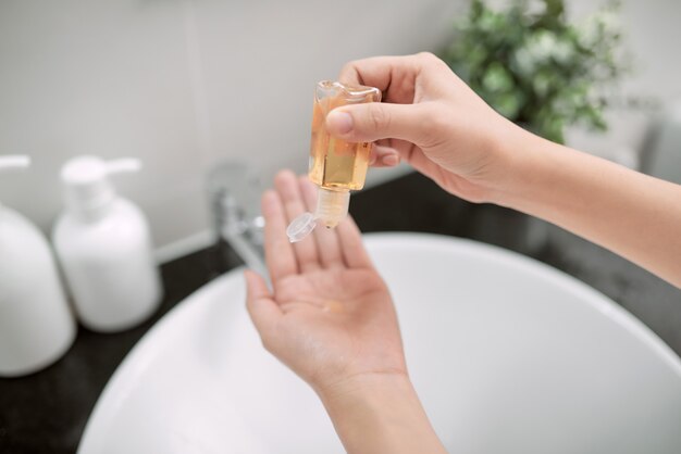 Femme à l'aide d'un désinfectant pour les mains dans la salle de bain