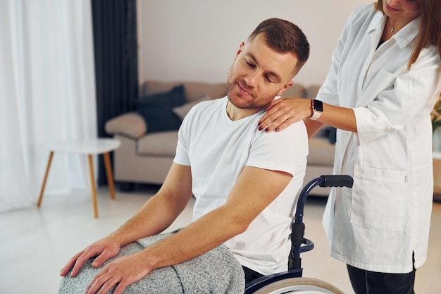 Une femme aide un homme handicapé en fauteuil roulant à la maison