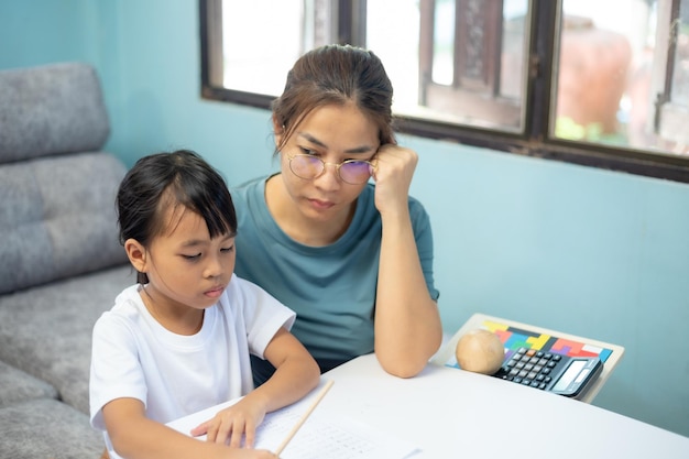 Une femme aide une jeune fille à faire ses devoirs.