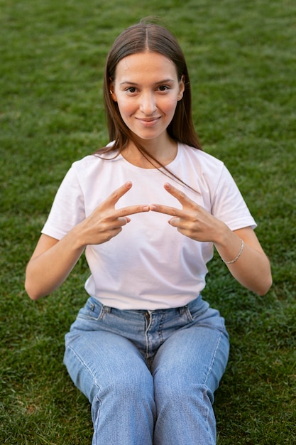 Photo femme à l'aide de la langue des signes à l'extérieur sur l'herbe