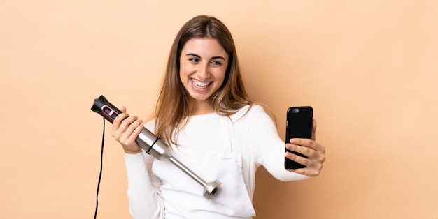 Femme à l'aide d'un mixeur plongeant faisant un selfie