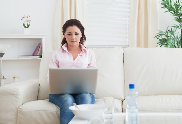 Femme à l&#39;aide d&#39;ordinateur portable sur le canapé