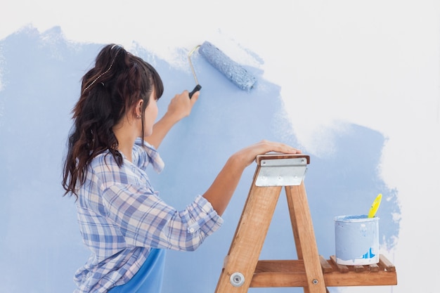 Femme à l&#39;aide de rouleau à peinture pour peindre le mur