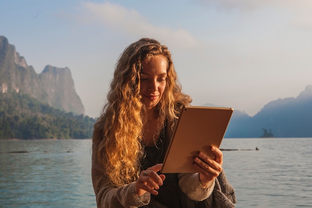 Femme à l&#39;aide de sa tablette au bord d&#39;un lac