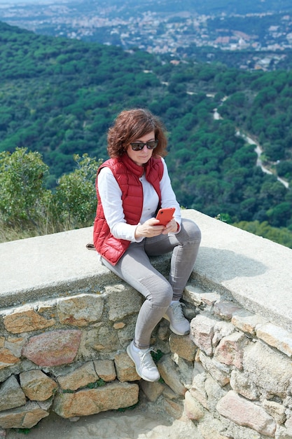 Femme à l'aide de son téléphone intelligent dans la montagne
