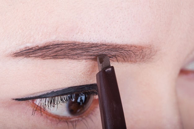 femme à l&#39;aide de sourcils de maquillage crayon