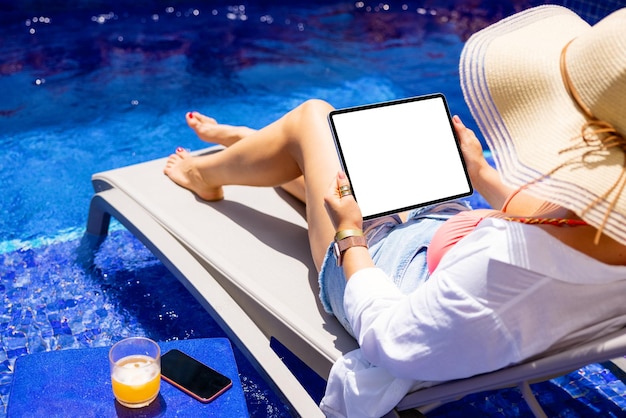Femme à l'aide d'une tablette au bord de la piscine