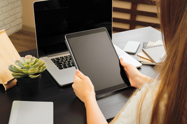 Femme à l'aide d'une tablette numérique, assis à une table dans un bureau