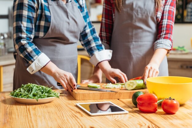 Femme à l'aide de tablette pour vérifier les recettes pendant la cuisson dans la cuisine