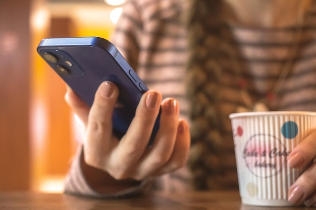 Femme à l'aide d'un téléphone mobile moderne dans un café public photo d'arrière-plan du concept de pause-café