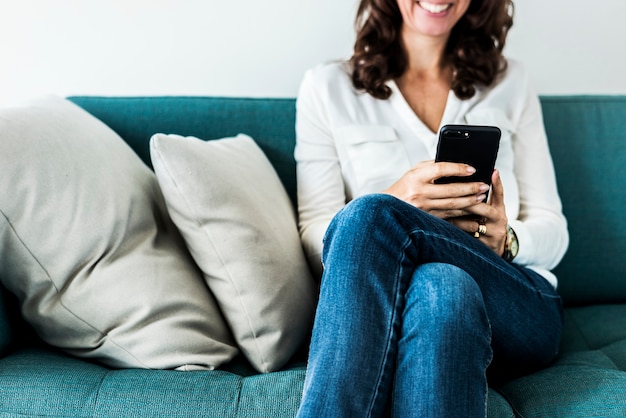 Femme à l&#39;aide de téléphone portable sur le canapé