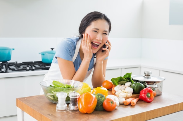 Femme à l&#39;aide de téléphone portable en face de légumes dans la cuisine