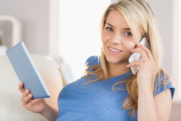 Femme à l&#39;aide de téléphone portable et tablette numérique à la maison