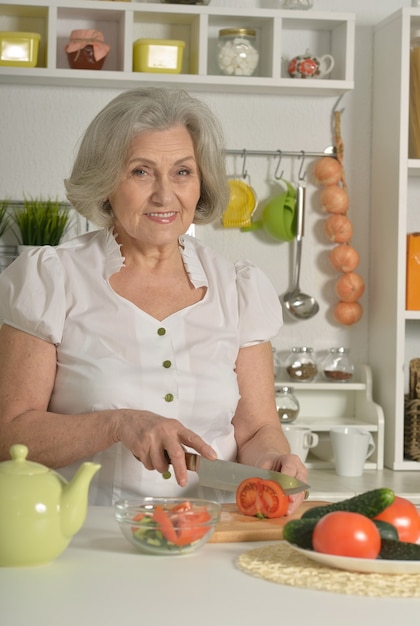 Femme aînée aux cheveux gris faisant cuire dans la cuisine