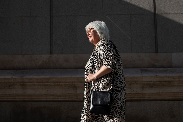 Femme aînée marchant au coucher du soleil dans la ville